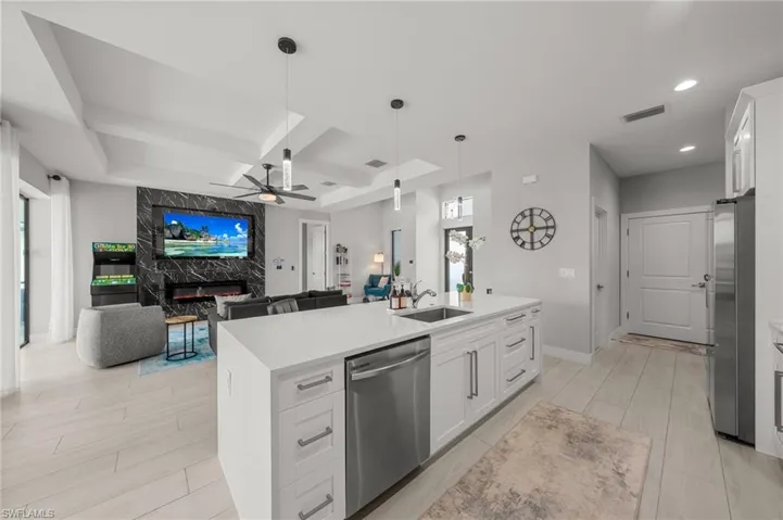 Kitchen featuring appliances with stainless steel finishes, ceiling fan, coffered ceiling, open floor plan, and wood tiled floors