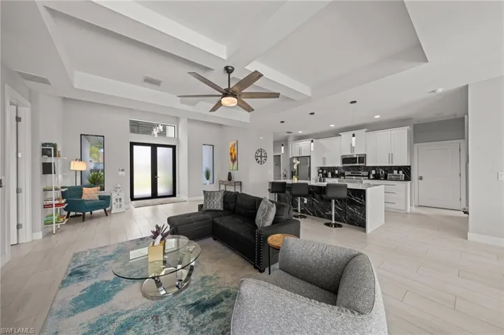 Living room featuring light wood-style floors, a ceiling fan, a raised ceiling, and recessed lighting