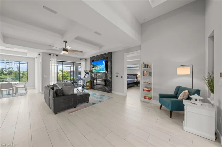 Living room with beamed ceiling, ceiling fan, coffered ceiling, and light wood finished floors
