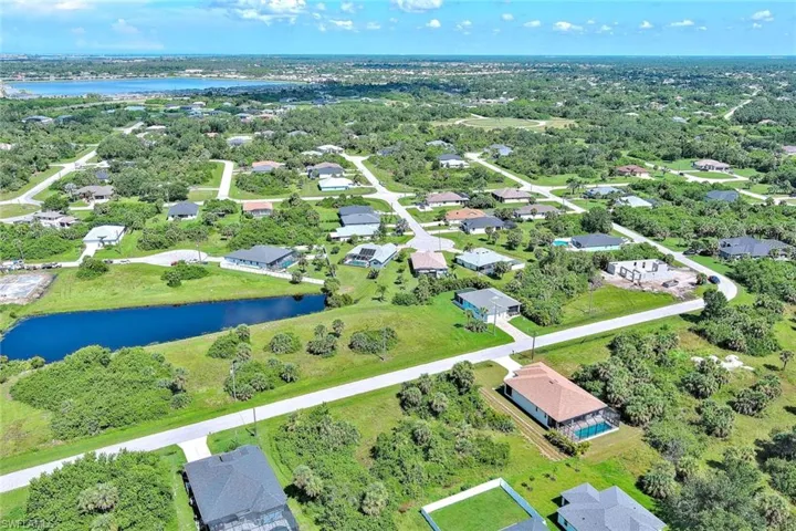 Aerial view of property and surrounding area featuring a large body of water and nearby suburban area
