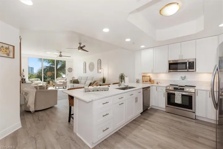 Kitchen featuring stainless steel appliances, a breakfast bar area, a peninsula, white cabinetry, and recessed lighting