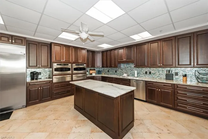 Kitchen featuring ceiling fan, stainless steel appliances, dark wood finish cabinetry, a paneled ceiling, and a warming drawer
