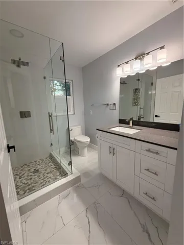 Bathroom 2 featuring a stall shower, vanity, and light marble finish floors