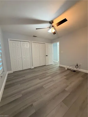 Unfurnished bedroom 3 with multiple closets, a ceiling fan, and wood finished floors