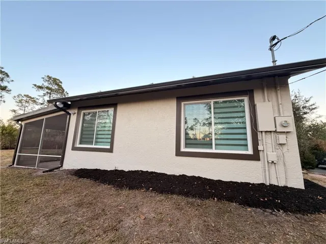 View of side of property with stucco siding and a sunroom