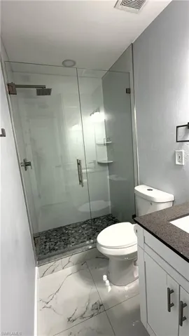 Bathroom 1 featuring vanity, a stall shower, and marble finish flooring