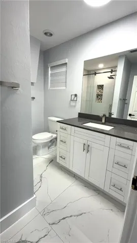 Full bathroom 1 featuring vanity, a shower stall, and light marble finish floors