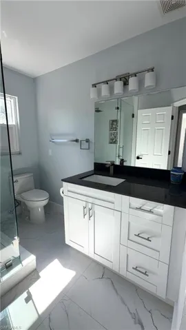 Bathroom 2 featuring vanity, a stall shower, and light marble finish flooring