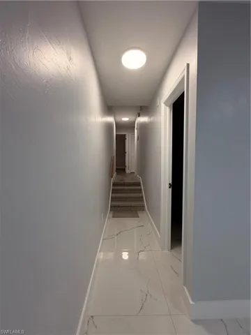 Hall featuring baseboards and light marble finish floors