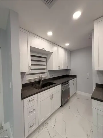 Kitchen featuring recessed lighting, white cabinets, light marble finish flooring, and dishwashing machine
