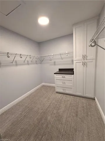 Walk in closet Master with light carpet and attic access