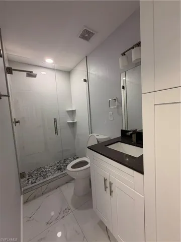 Full bath 1 with a shower stall, vanity, and light marble finish flooring