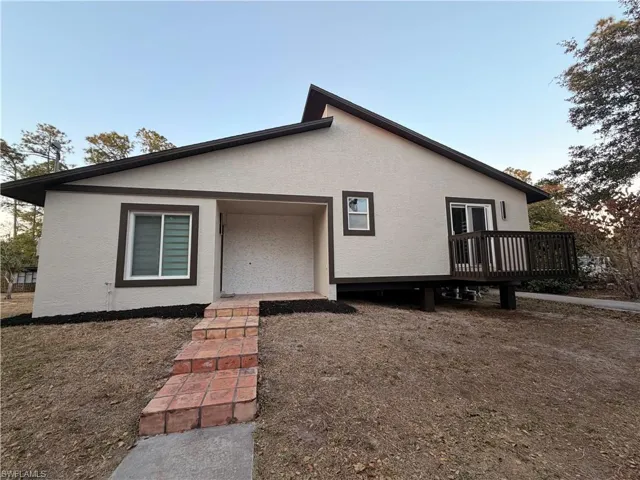 View of front facade with stucco siding and a deck