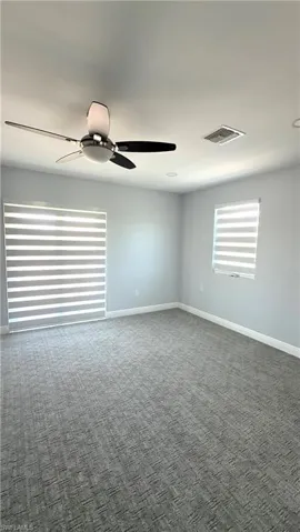 Carpeted spare room with baseboards and ceiling fan