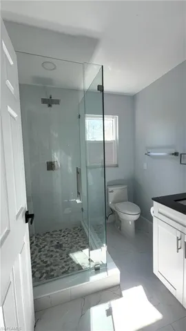Full bathroom 2 featuring light marble finish floors, a stall shower, and vanity