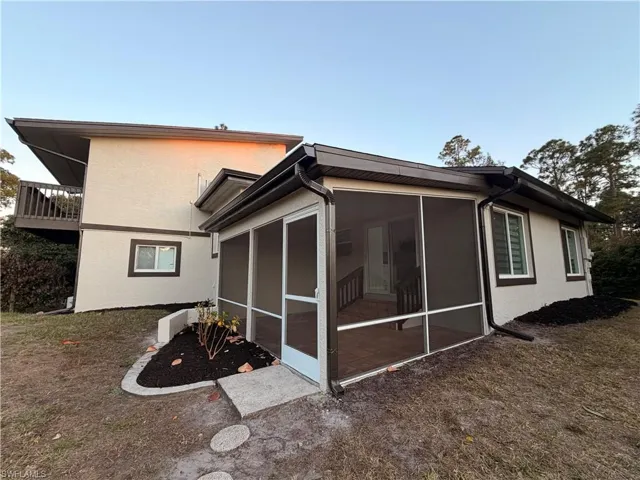 Back of house with stucco siding and a sunroom