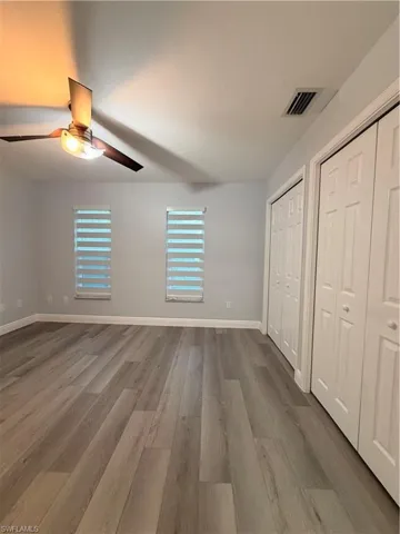 Unfurnished bedroom 3 featuring two closets, light wood-style flooring, and a ceiling fan