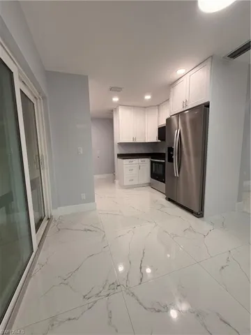 Kitchen/ Diningroom featuring white fridge, white cabinets, dark countertops, recessed lighting, and range
