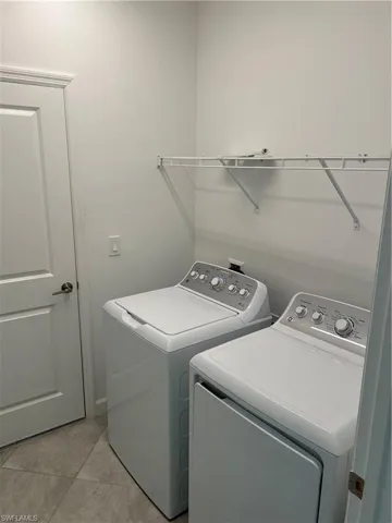 Dedicated laundry space featuring a white top-load washing machine, a white front-load dryer, and an overhead wire shelf