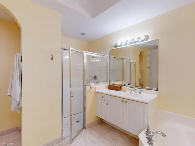 Bathroom with tile flooring, separate shower and tub, and vanity