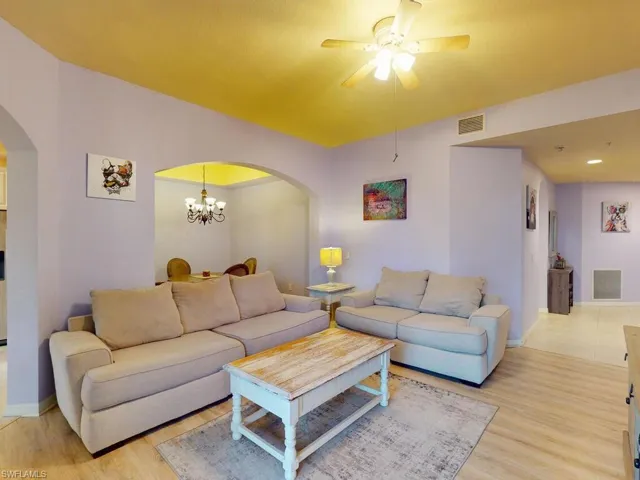 Living room with tile flooring and ceiling fan with notable chandelier