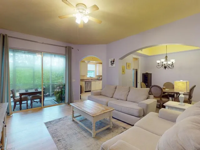 Living room featuring ceiling fan with notable chandelier and light hardwood / wood-style floors