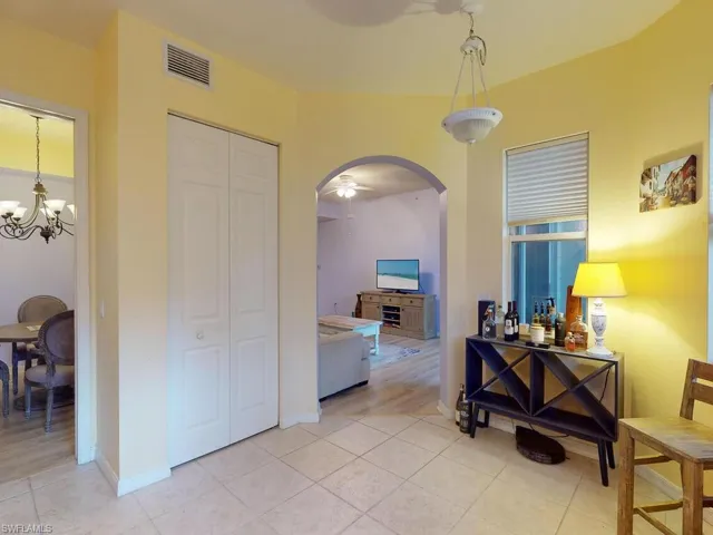 Corridor with a notable chandelier and light tile flooring