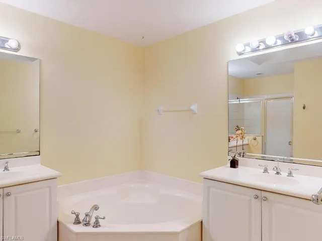 Bathroom featuring a bath, vanity with extensive cabinet space, and double sink