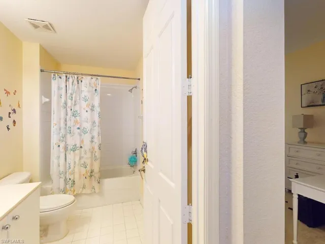 Full bathroom featuring tile flooring, vanity, toilet, and shower / bath combo with shower curtain