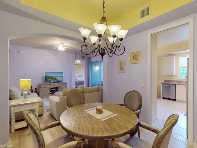 Dining room with light hardwood / wood-style floors and ceiling fan with notable chandelier