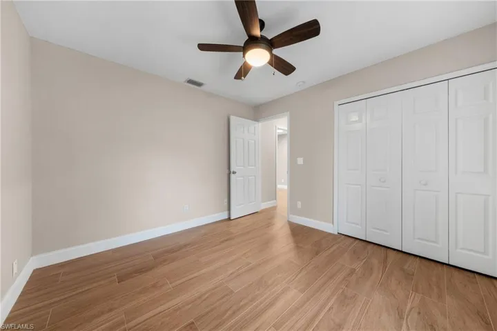 Spacious room featuring wood-finish flooring, a contemporary ceiling fan with integrated lighting, and bi-fold closet doors