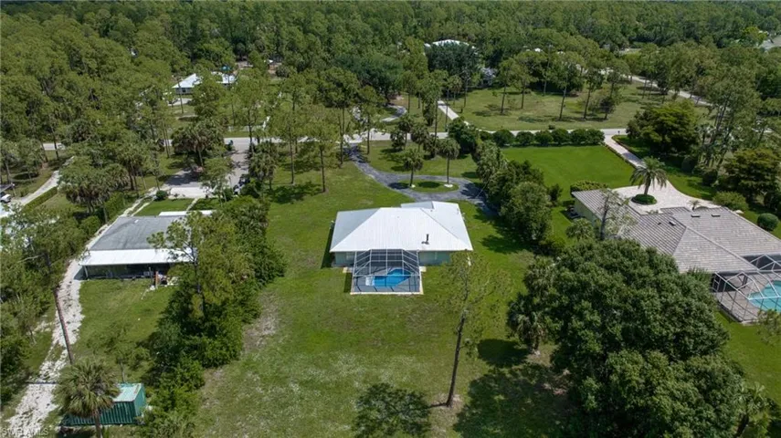 Aerial perspective showcasing a single-story residence with a screened pool enclosure and a white pitched roof