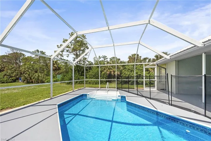 Screen-enclosed pool area featuring a rectangular pool with steps and a safety fence