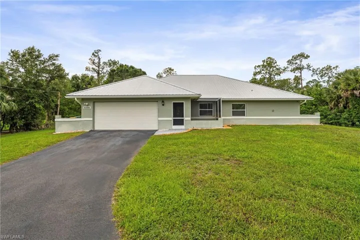 Ranch-style residence featuring a light green exterior, an attached garage, a paved driveway, a metal roof, and a screened entry