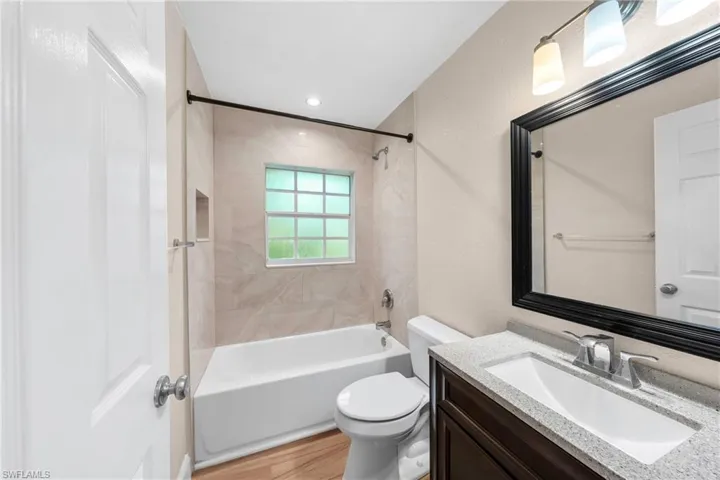 Full bathroom featuring a tub-shower combination with tiled surround, a recessed niche, and a window for natural light