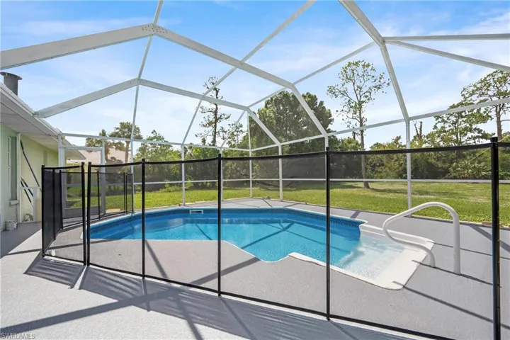 Screened pool enclosure with a rectangular swimming pool featuring a built-in spa
