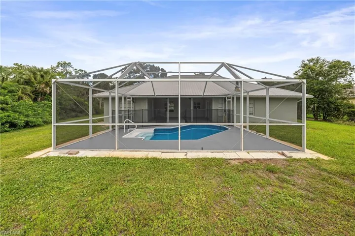 Screened enclosure featuring a swimming pool with integrated spa and surrounding concrete decking