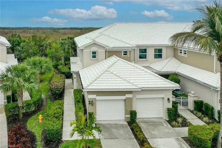 View of front of property featuring driveway, a tile roof, a gate, and stucco siding
