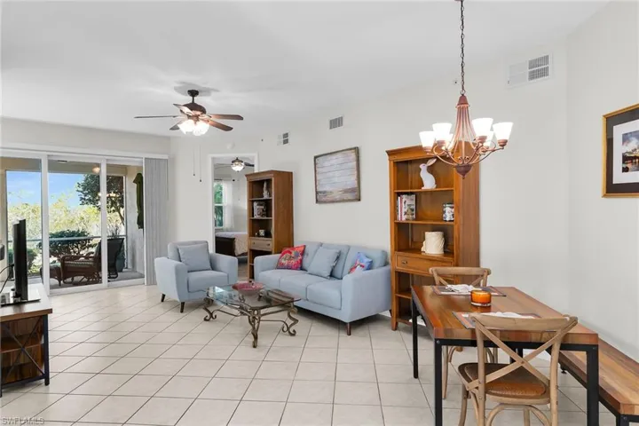 Living room with ceiling fan, suspended lighting, and light tile patterned flooring