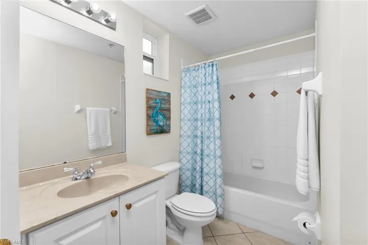 Full bathroom featuring vanity, shower / bath combo with shower curtain, and light tile patterned floors