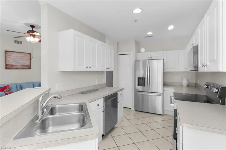 Kitchen featuring stainless steel appliances, white cabinets, light countertops, a ceiling fan, and light tile patterned floors