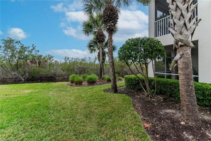 View of grassy yard featuring a sunroom and a balcony