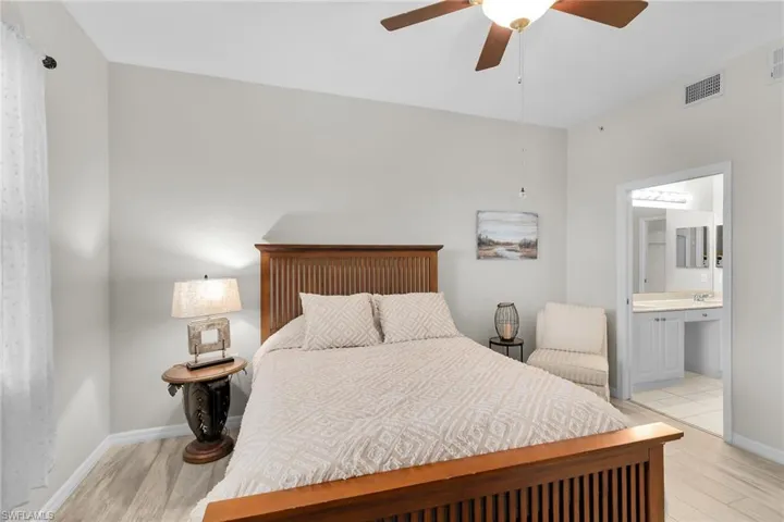 Bedroom with light wood-type flooring, a ceiling fan, and connected bathroom