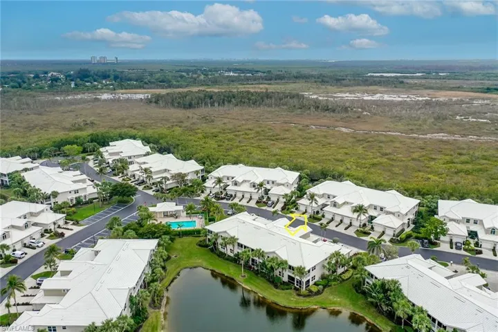 Aerial view of residential area featuring a forest and a nearby body of water