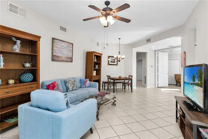 Living area with light tile patterned flooring, a ceiling fan, and suspended lighting