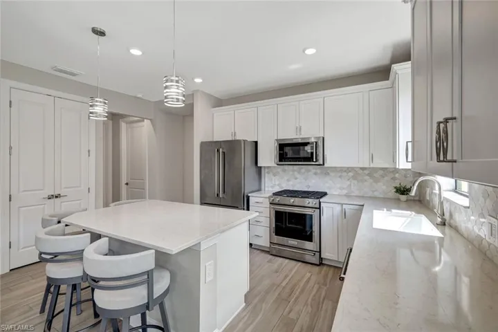 Stunning kitchen with stainless steel appliances and finishes, tasteful backsplash, kitchen breakfast bar, and island