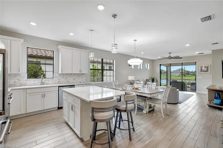 Kitchen with a center island, white cabinets, open floor plan, decorative light fixtures, and recessed lighting