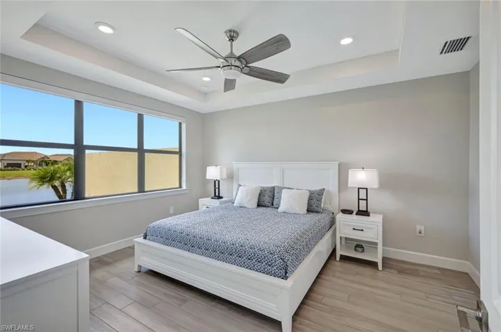 Primary bedroom featuring a tray ceiling, tile flooring, a ceiling fan, and recessed lighting