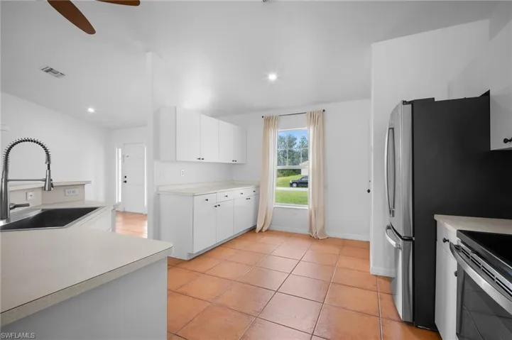 Kitchen featuring light countertops, light tile patterned floors, white cabinetry, stainless steel appliances, and recessed lighting