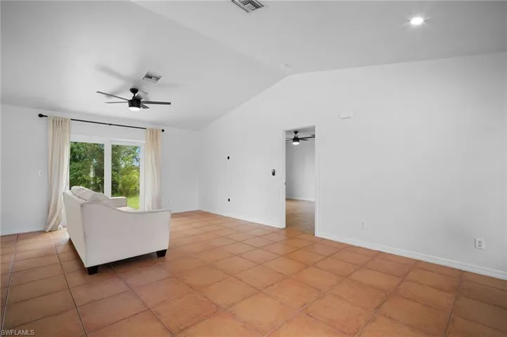 Unfurnished living room featuring vaulted ceiling and light tile patterned floors